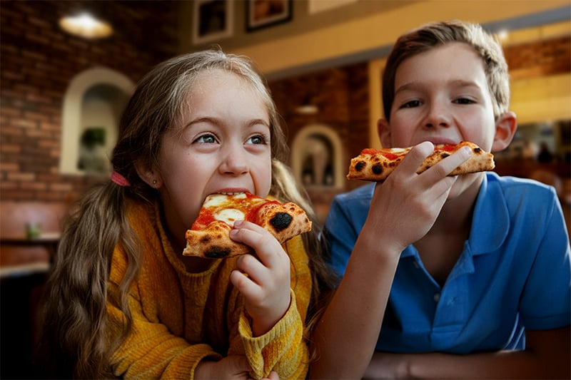 Šťastné děti jedící pizzu v Papaiolo z dětského menu